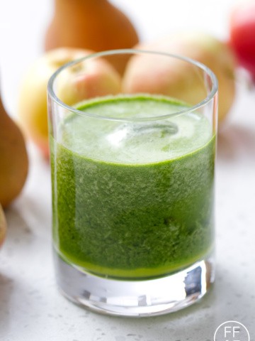 glass of green juice in front of fruit
