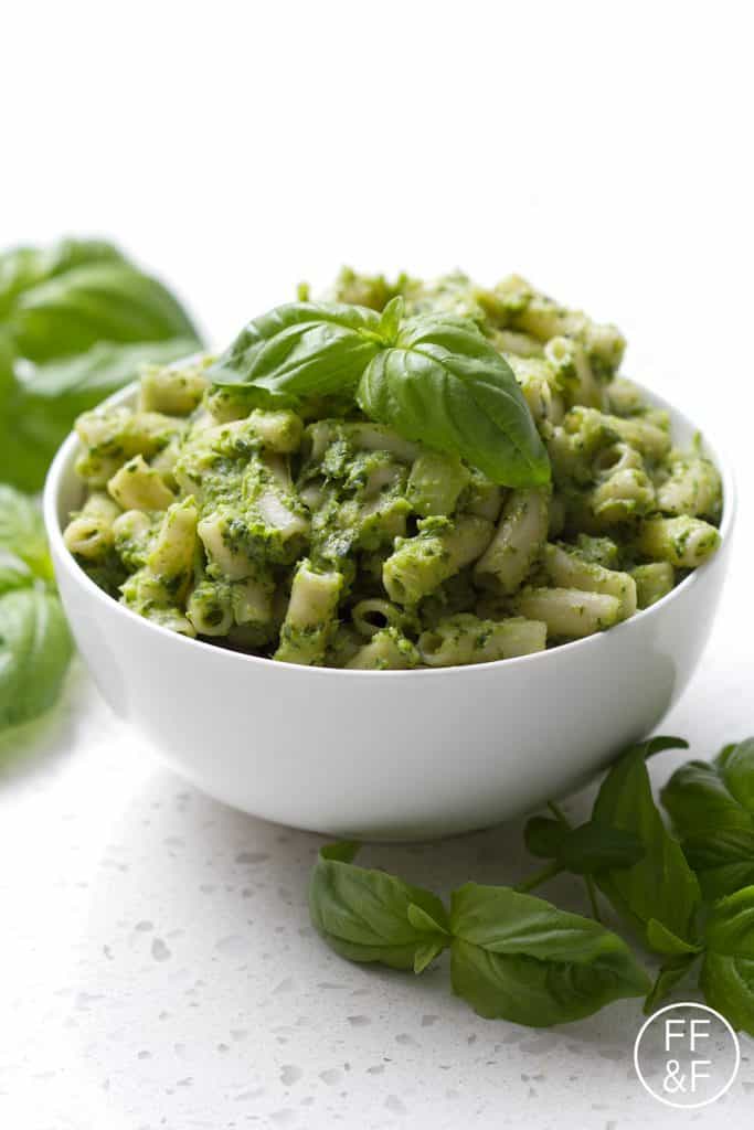 pesto pasta in bowl garnished with basil leaves