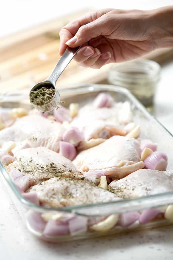 sprinkling dried herbs over chicken
