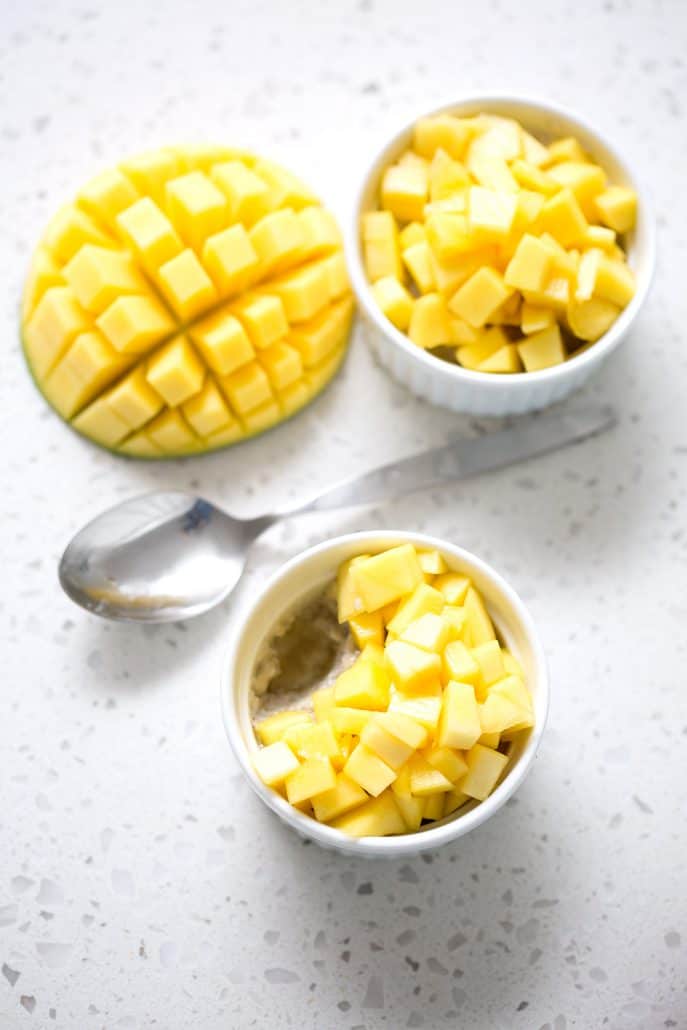 sliced mango with chopped mango in ramekins with spoon