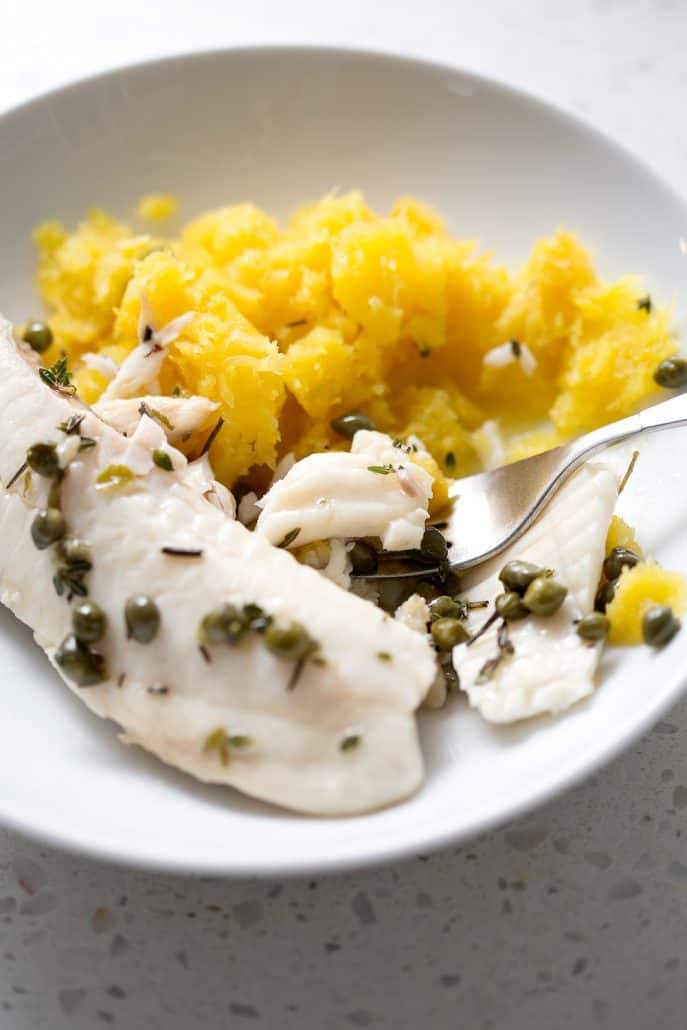 plate of mashed squash and fish with capers and seasonings with fork