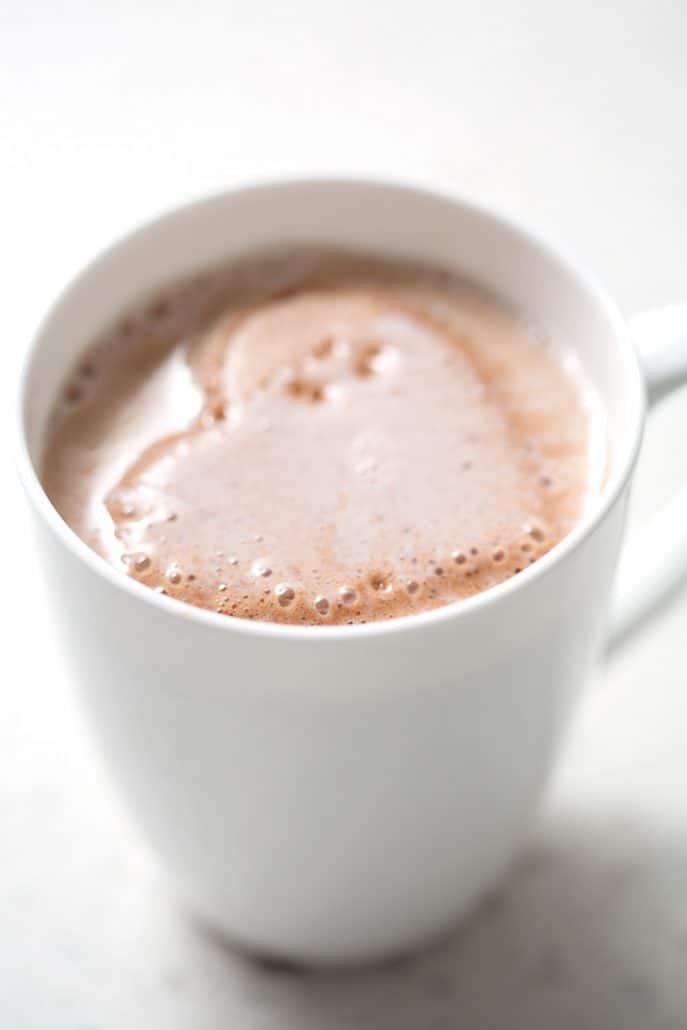 melting heart shaped chocolate marshmallow in mug on white background