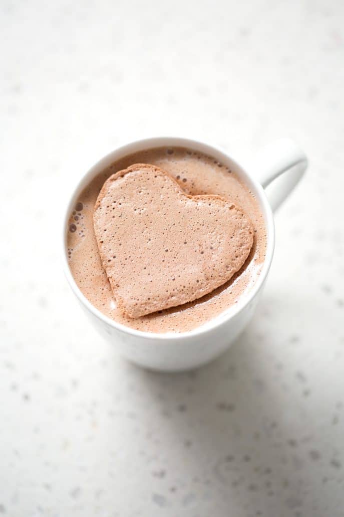 heart shaped chocolate marshmallows melting in mug on white background