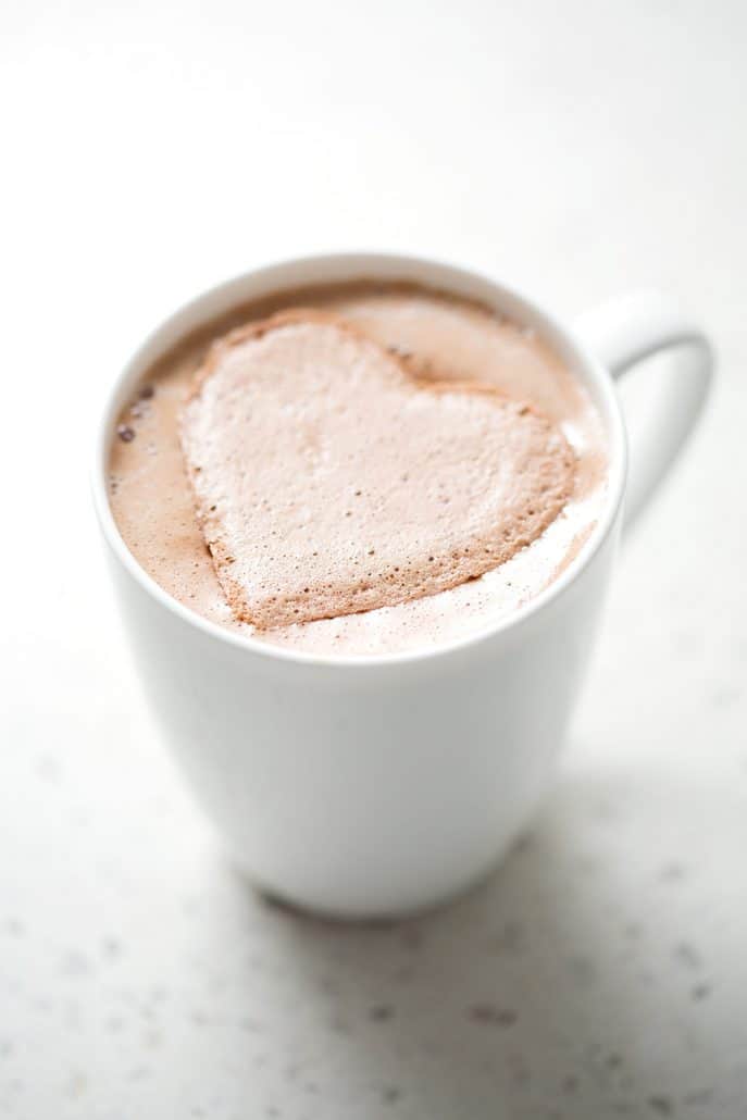 heart shaped marshmallow in white mug on white background