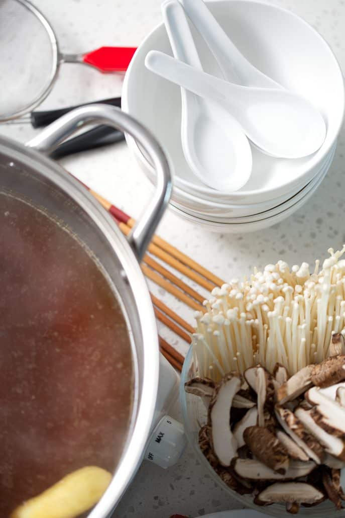 porcelain spoons, bowls, chopsticks and mushrooms around hot pot