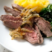 sliced flank steak with cooked onions, spinach and squash in bowl