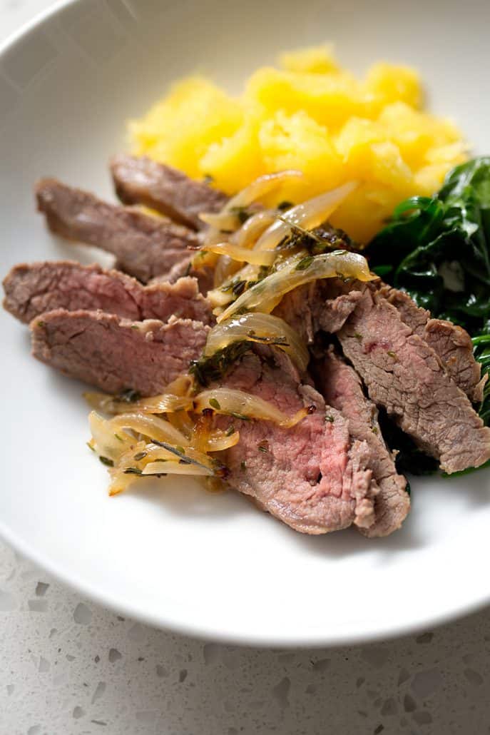 sliced flank steak with cooked onions, spinach and squash in bowl