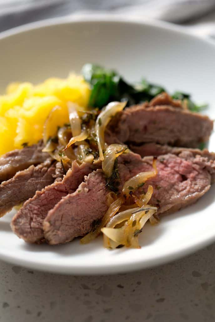 sliced flank steak with cooked onions, spinach and squash in bowl