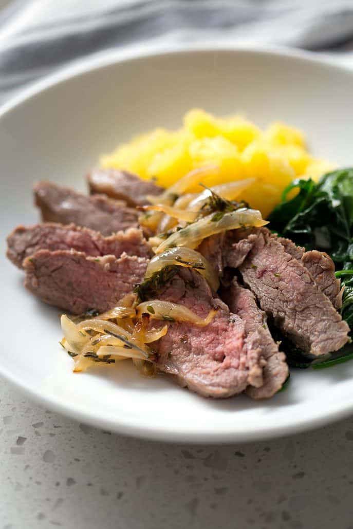 sliced steak with cooked onions, spinach and squash in bowl