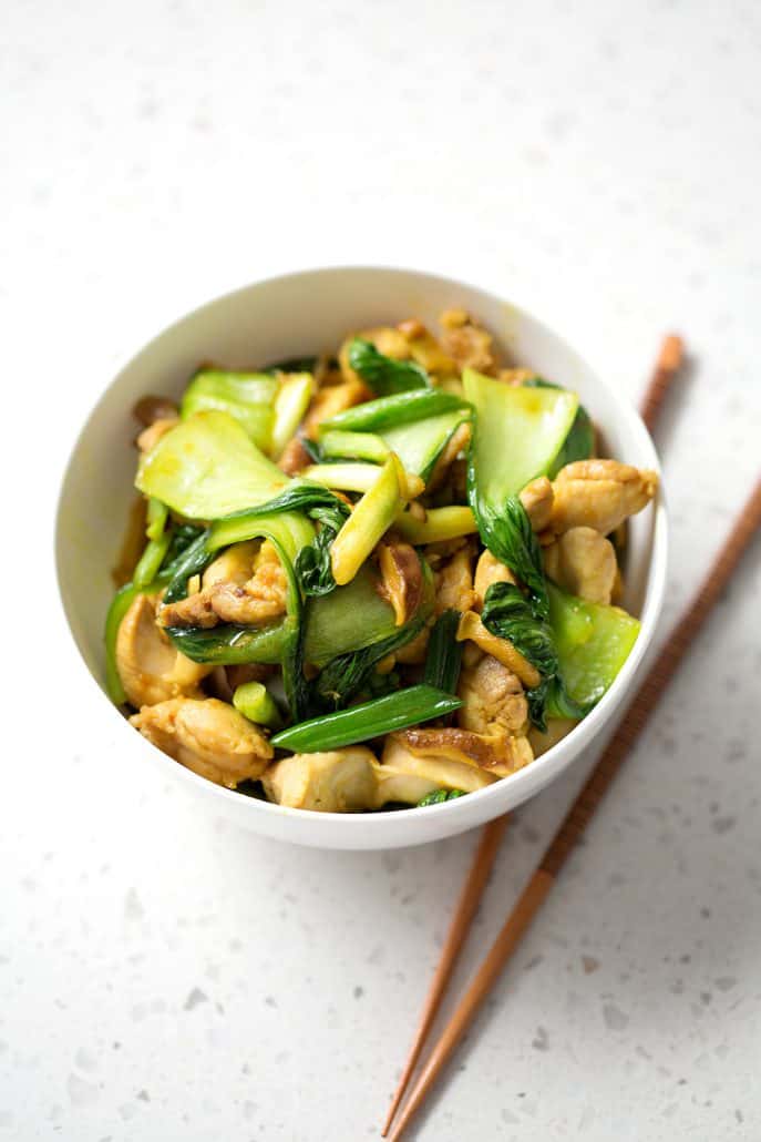 stir fry in white bowl with chopsticks on white background
