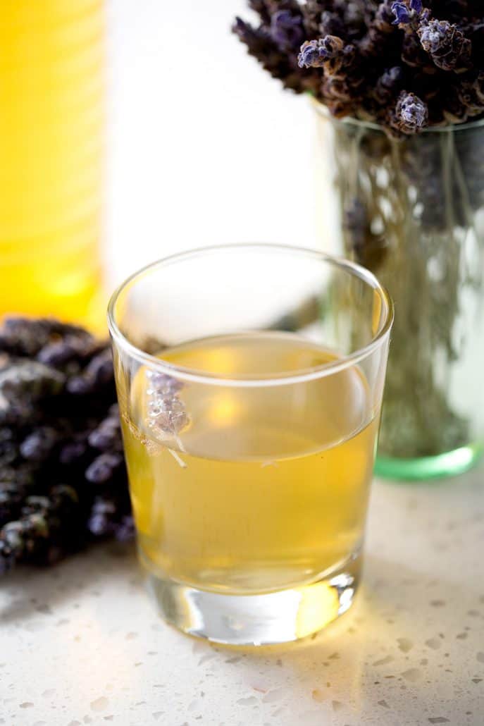 glass of kombucha tea with lavender bunches on white background