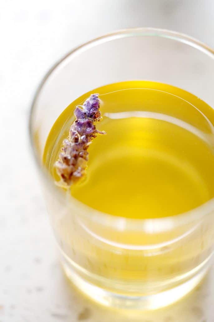glass of kombucha tea with lavender flower floating on white background