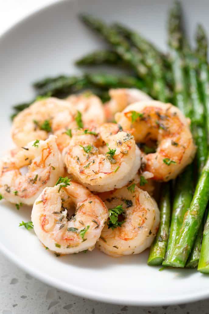 plate of seasoned shrimp with asparagus on white background