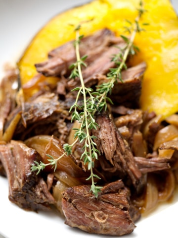 shredded beef on acorn squash with sprigs of thyme
