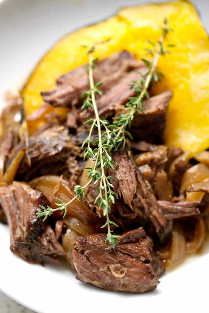shredded beef on acorn squash with sprigs of thyme