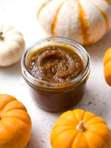 pumpkin butter on white background with mini pumpkins