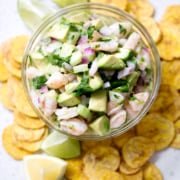 bowl of ceviche surrounded by plantain chips and lime