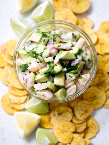 bowl of ceviche surrounded by plantain chips and lime