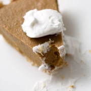 piece of pumpkin pie with dollop of cream on white plate