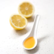 spoonful of juice with lemon halves on white background