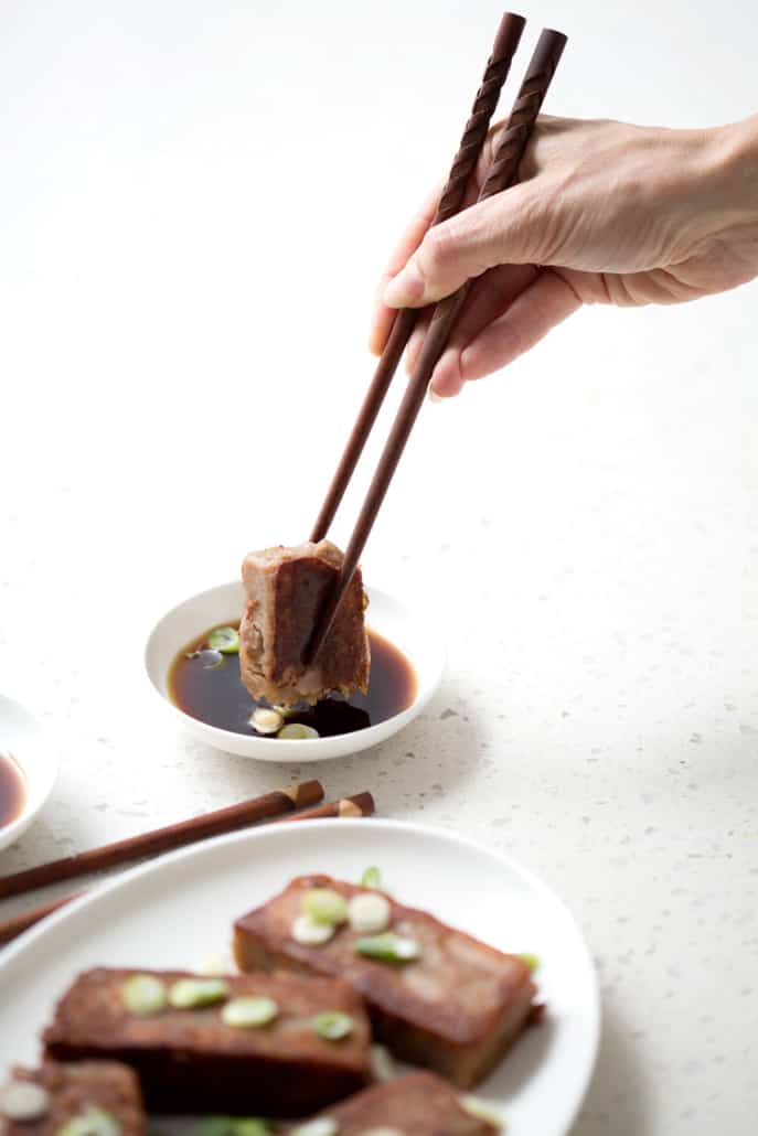 using chopsticks to dip the taro cake into the dip