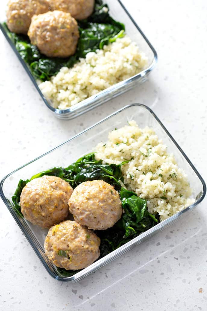 meatballs, spinach and rice in glass portable dishes on white counter