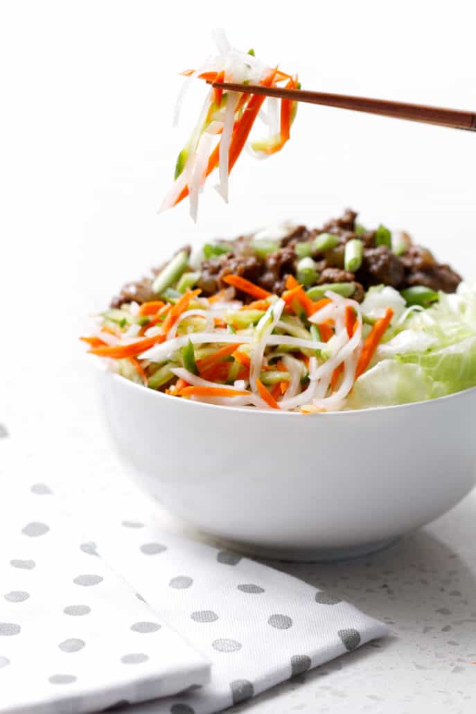 bowl of lettuce, shredded vegetables and ground beef with chopsticks