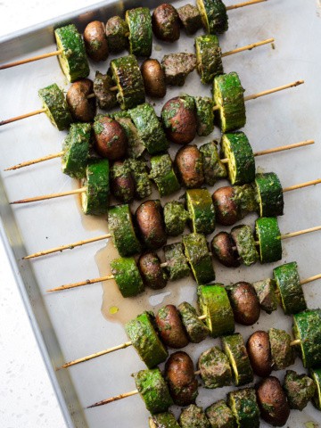 grilled meat skewers with vegetables on baking sheet
