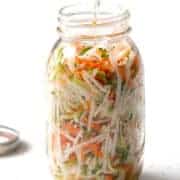shredded vegetables in a large mason jar on white counter