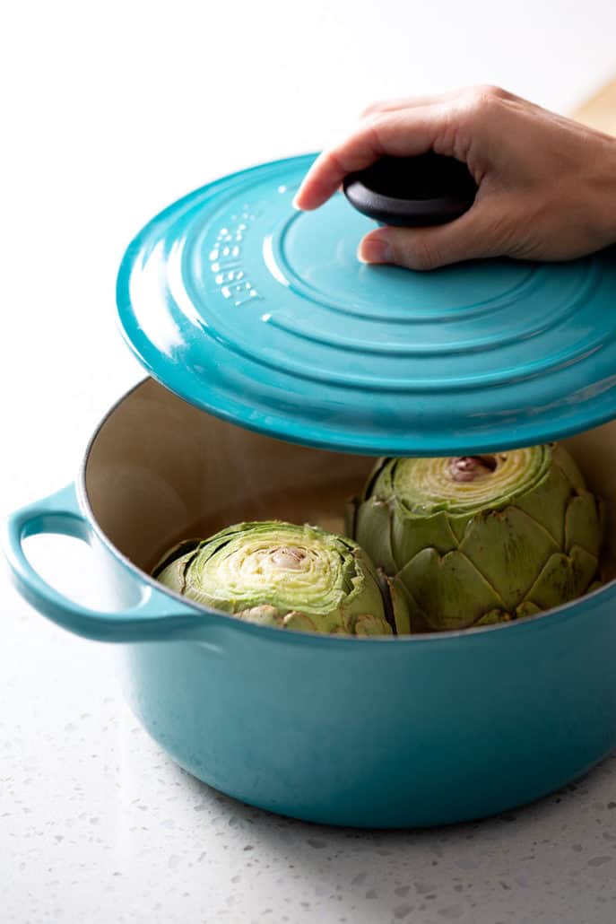 putting cover on artichoke filled dutch oven