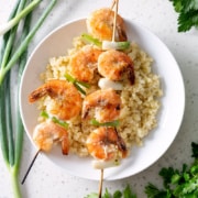 grilled garlic shrimp skewers on bed of rice on white plate