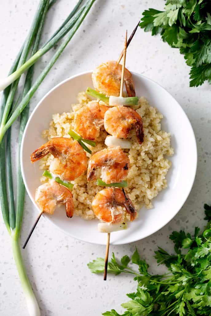grilled shrimp and onion skewers on plate with rice 