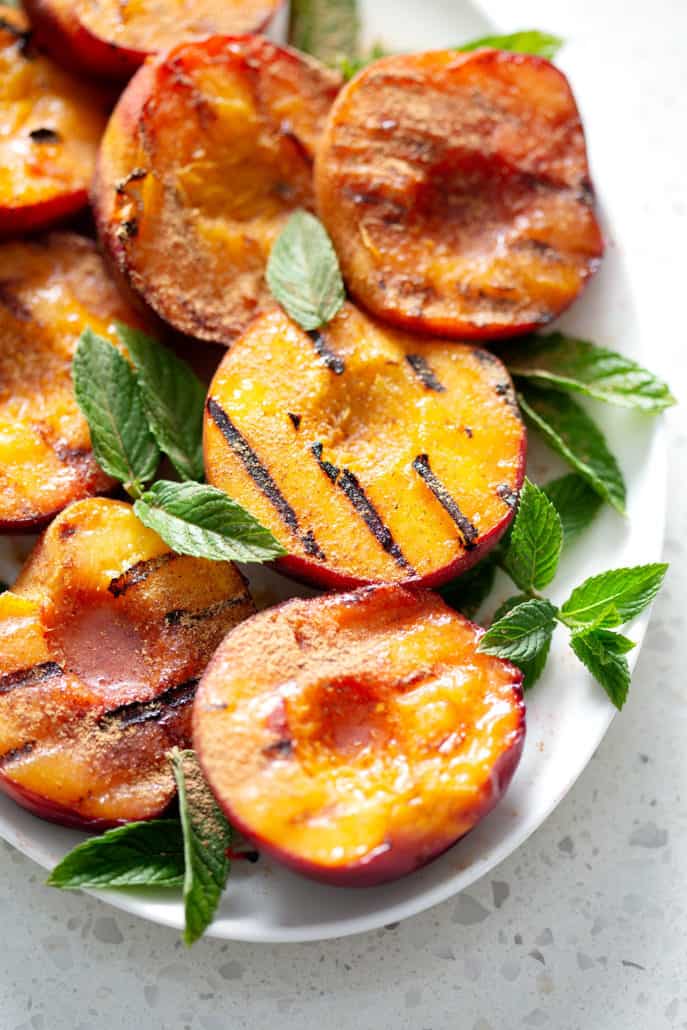 grilled peaches on platter garnished with mint leaves