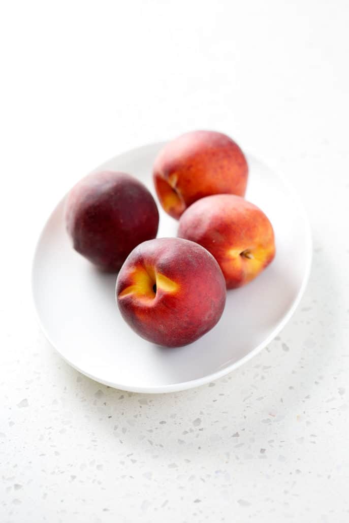fresh peaches on white platter on white counter