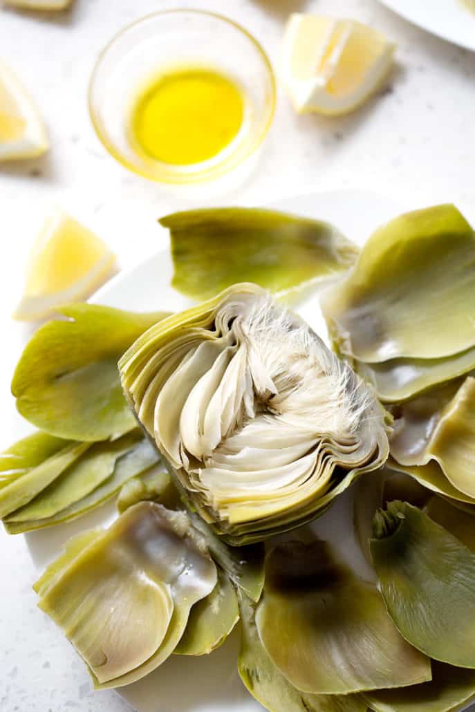 artichoke halved and cooked alongside a small bowl of artichoke dipping sauce