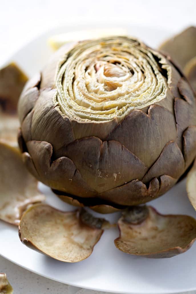 close up of whole baked artichoke on plate