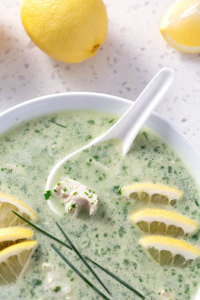 close up of green soup surrounding by lemons