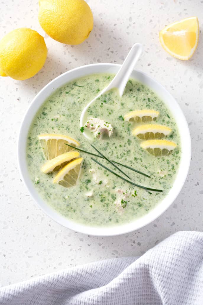 bowl of green soup garnished with lemons and chive from above