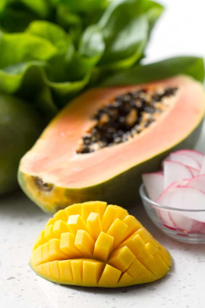 still life of lettuce, papaya and mango on white background