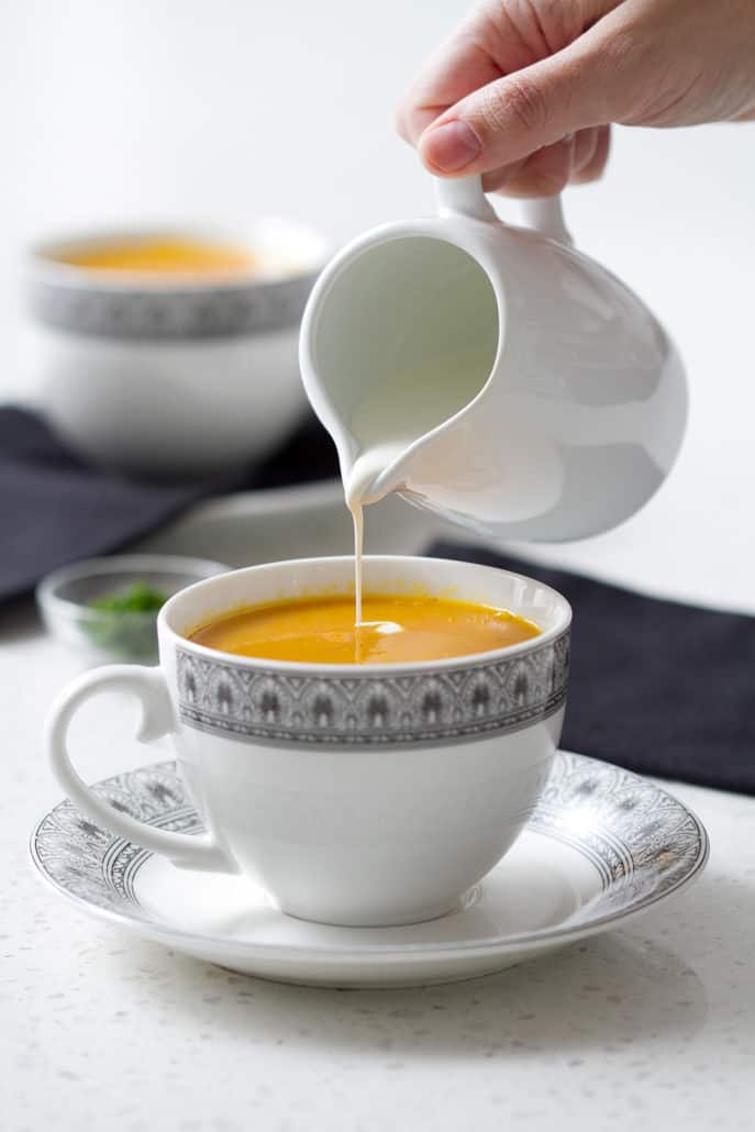 pouring cream into cup of soup