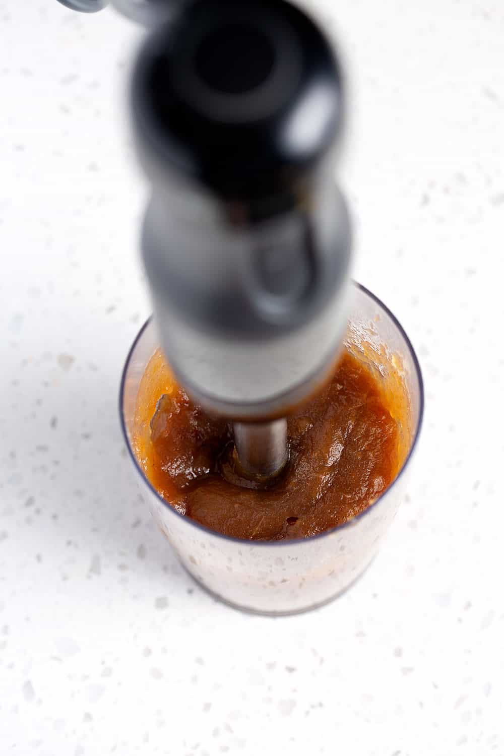instant pot apple butter being pureed by immersion blender