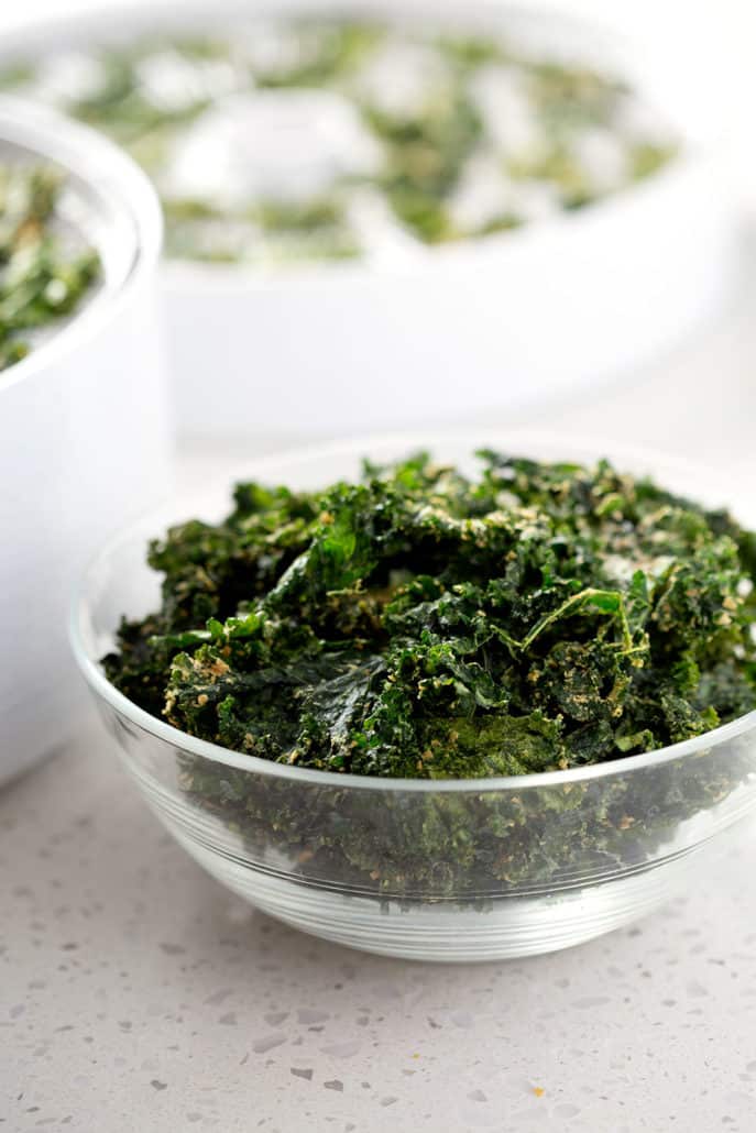 bowl of kale chips in front of dehydrator