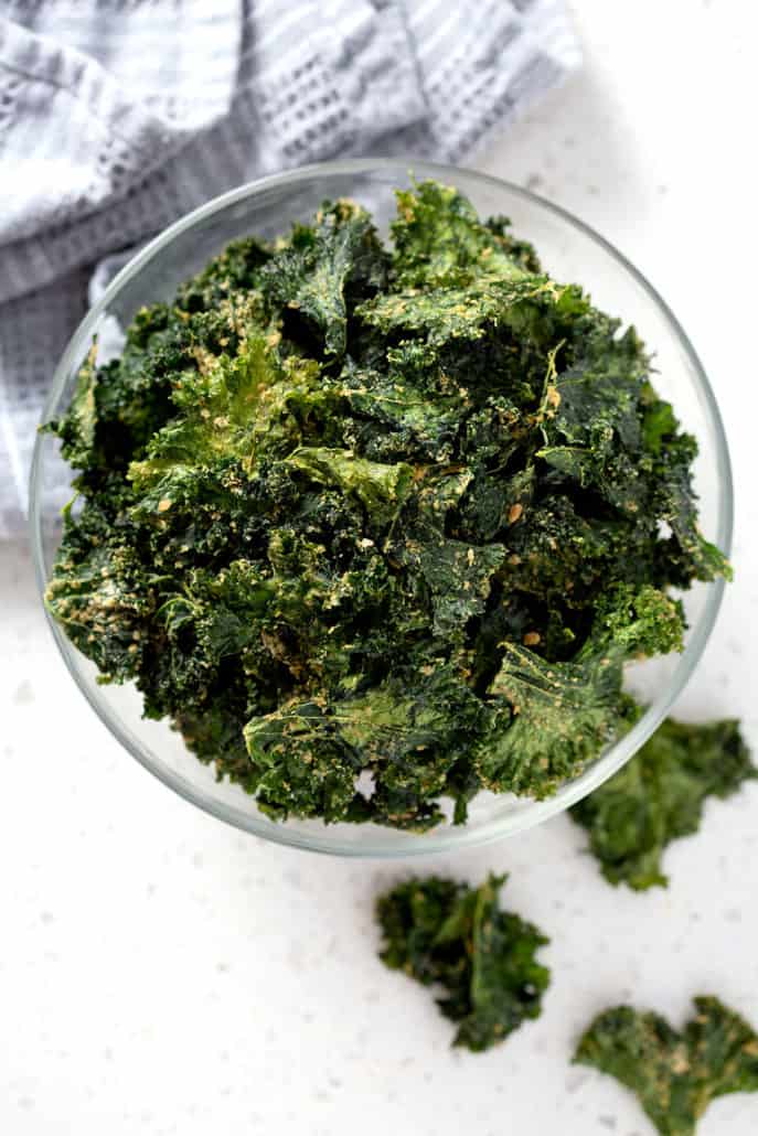 bowl of kale chips from above surrounded by towel and additional chips