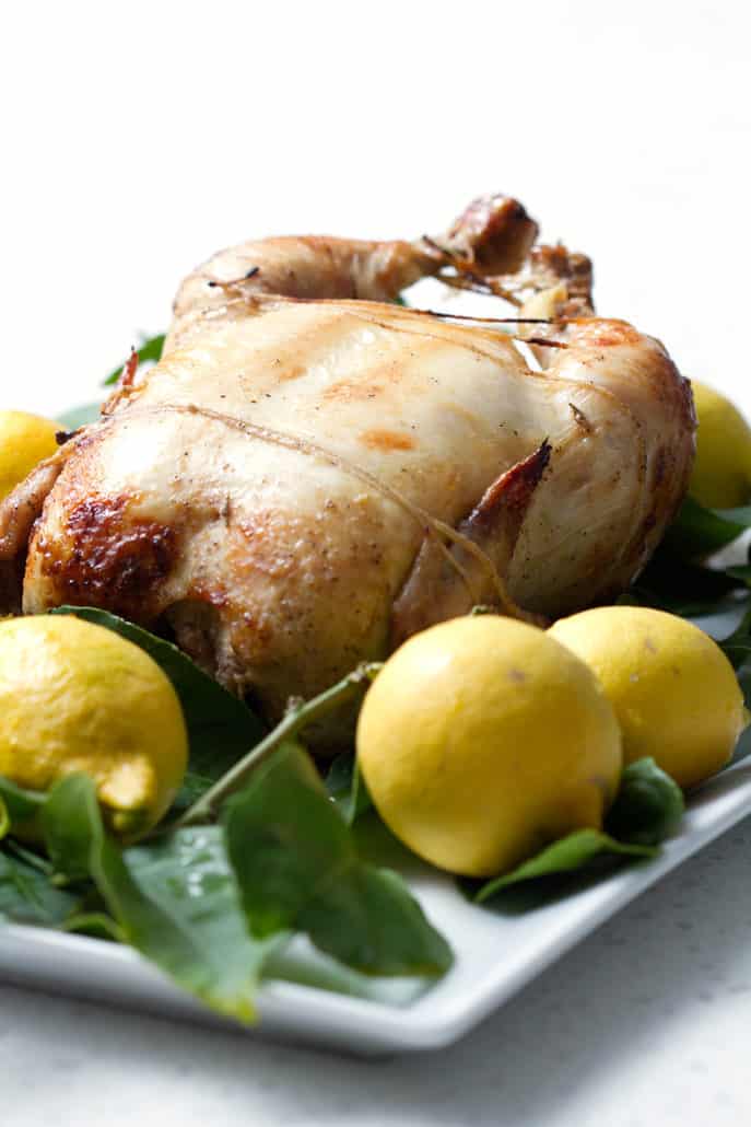 whole roasted chicken surrounded by lemons