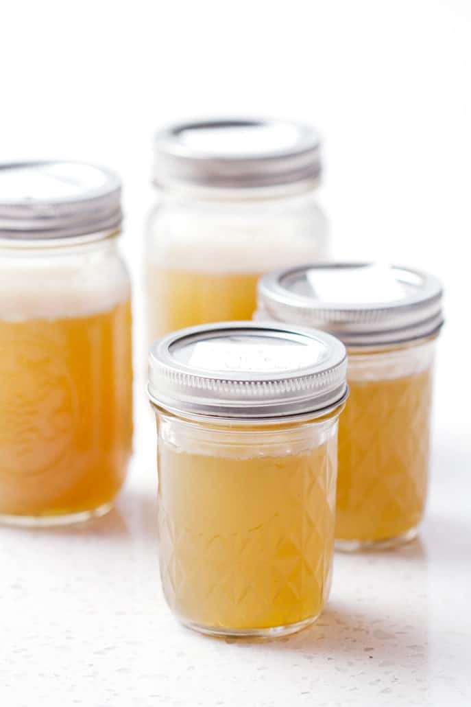 mason jars filled with healing chicken broth on white background