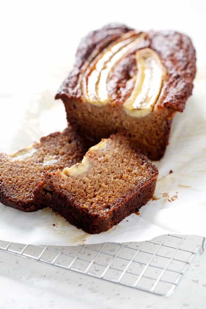 AIP banana bread loaf with slices on parchment and wire rack
