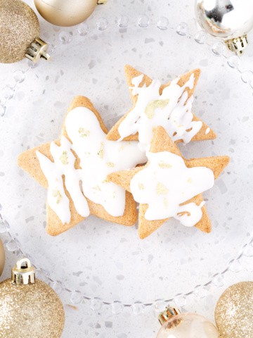 plate of cut out sugar cookies surrounded by gold ornaments