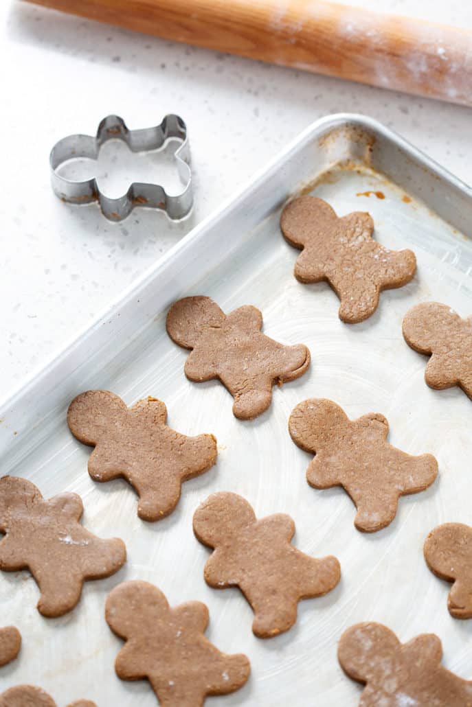 baking sheet of aip gingerbread cookies with rolling pin and cookie cutter