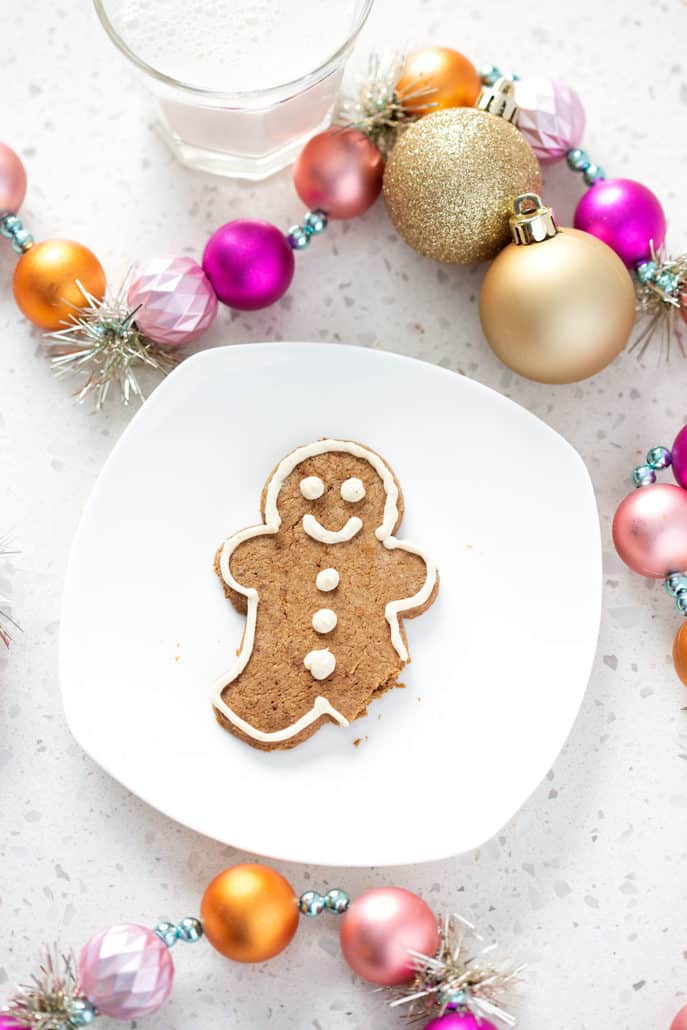aip gingerbread cookie on white plate surrounded by Christmas ornaments