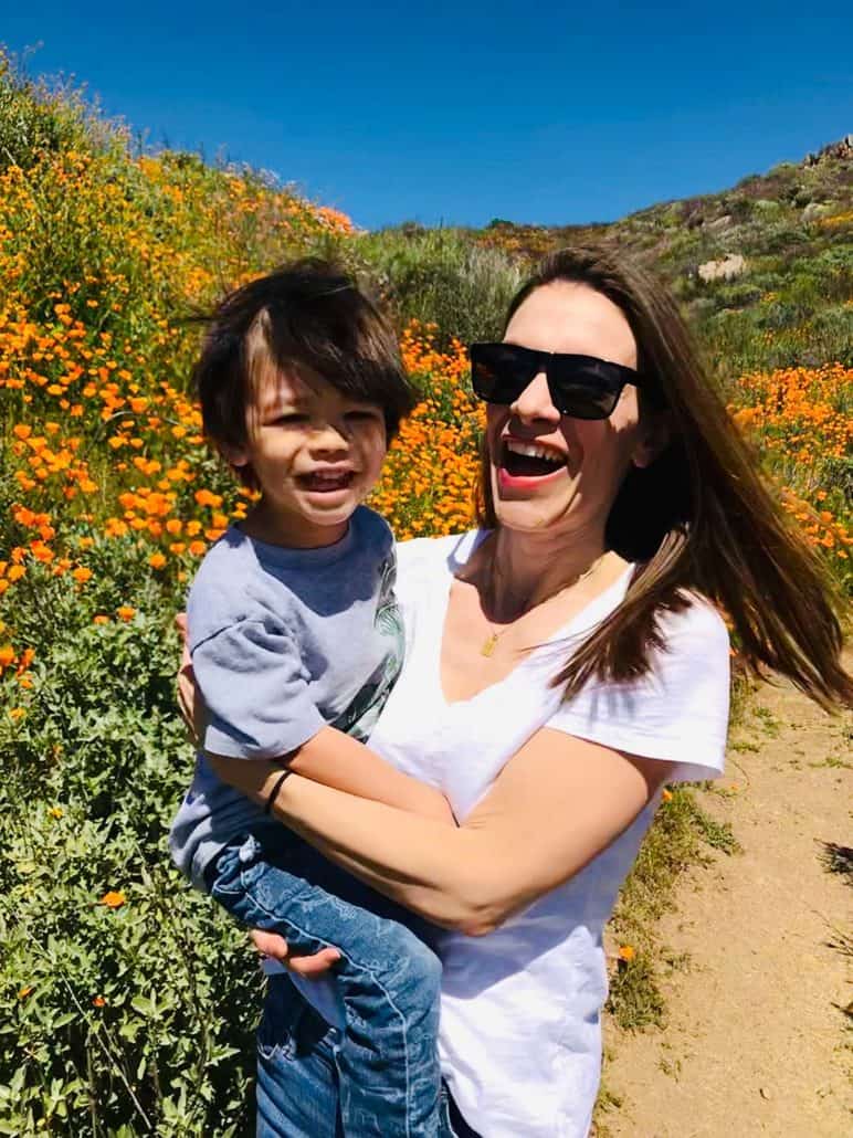 mother holding son smiling in front of a hillside of orange poppies